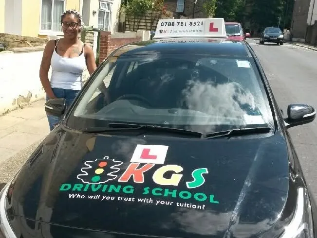 Pupil standing next to the KGS Driving School car on a sunny day