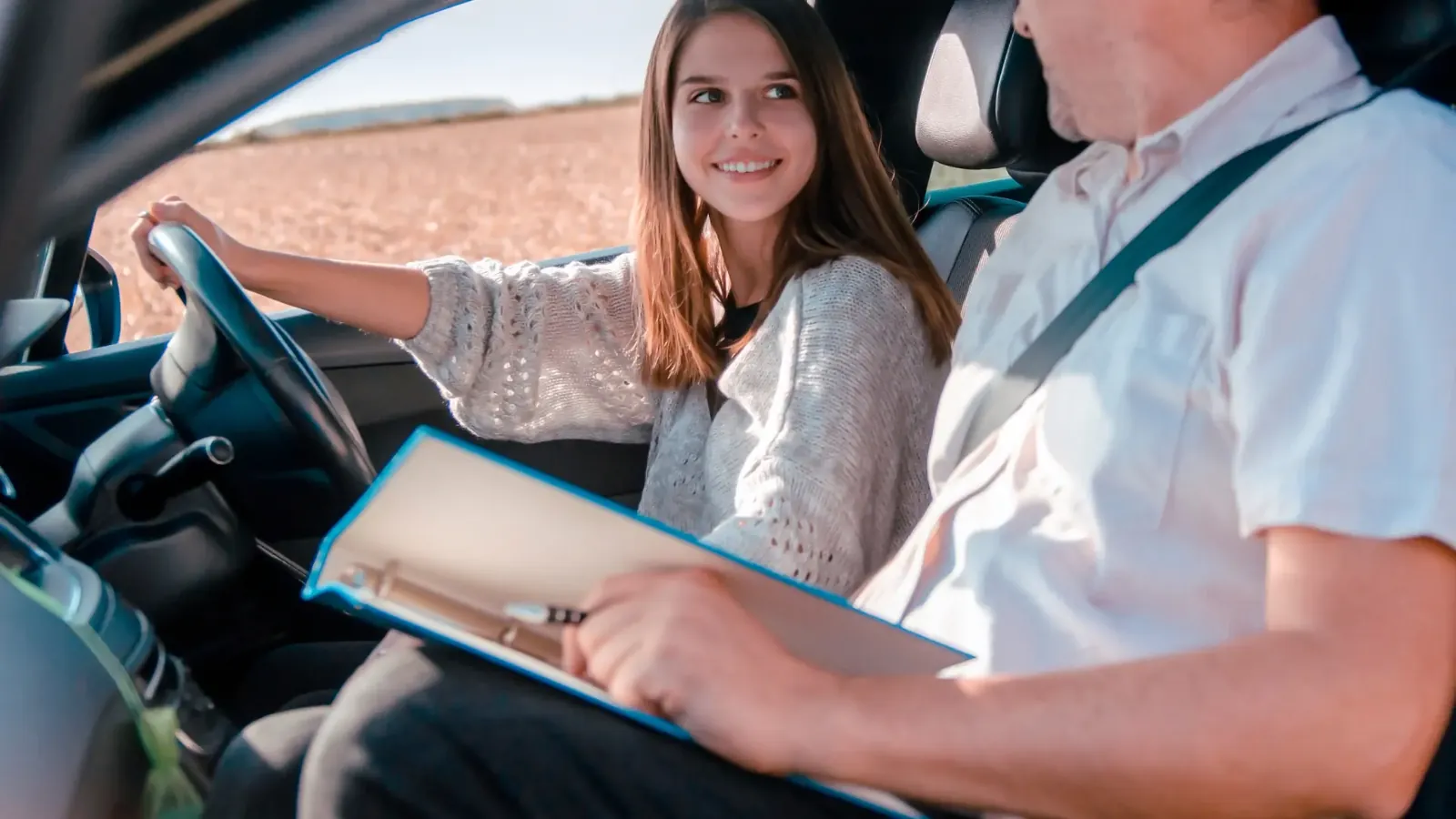 Smiling learner driver relaxed beside her calm driving instructor
