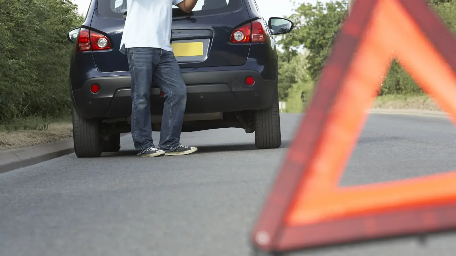 Broken-down car behind a warning triangle, a typical road hazard