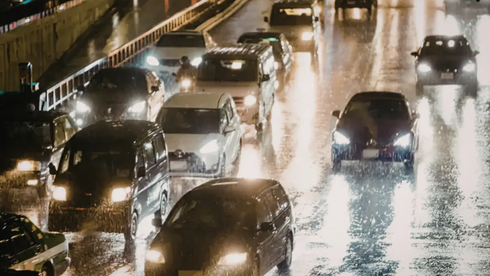 Cars with headlights on driving through rain at night
