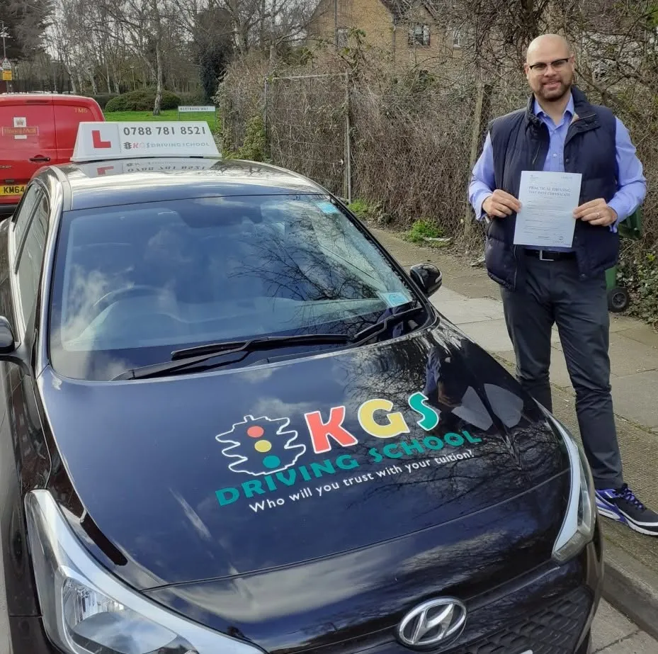 Pupil holding his pass certificate next to the KGS Driving School car