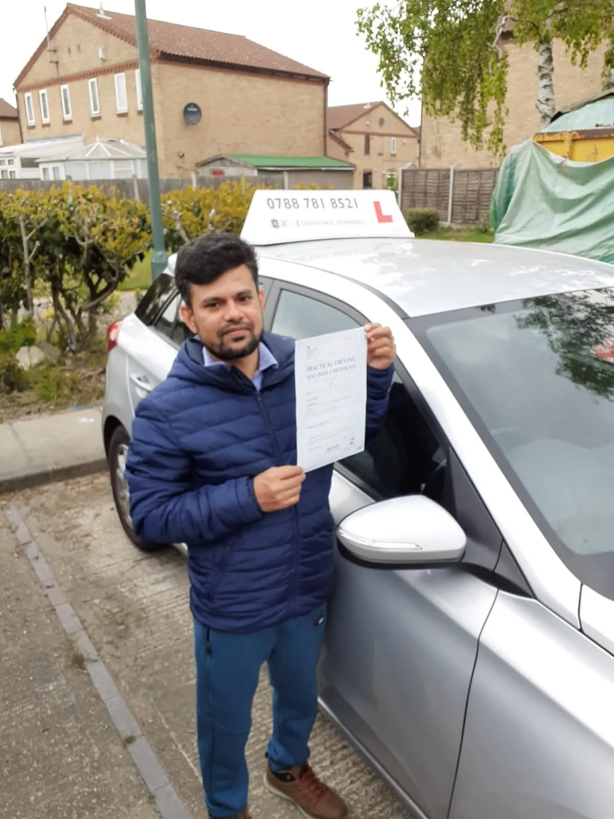 Pupil holding his driving test pass certificate beside the KGS learner car