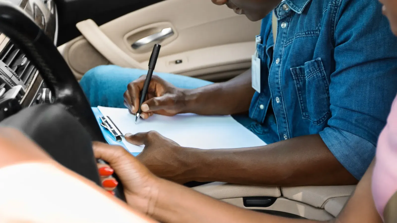 Examiner marking a mock driving test sheet in the car