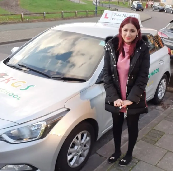 Pupil standing beside the KGS Driving School car after passing her test