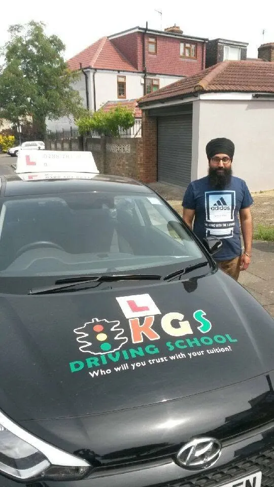 Pupil standing next to the KGS Driving School car after his driving test