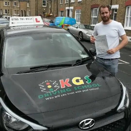 Pupil holding his pass certificate by the KGS Driving School car